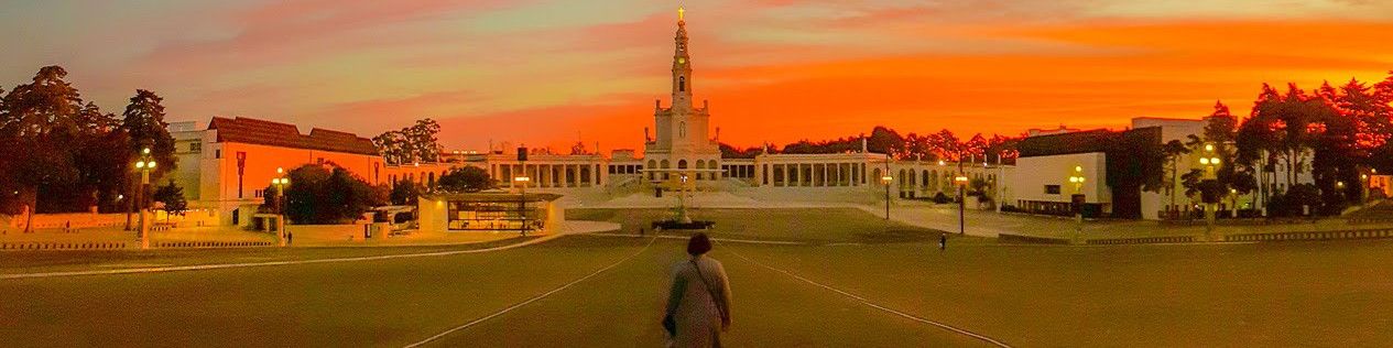 The Sanctuary of Fátima at sunset, with a person walking towards the basilica.